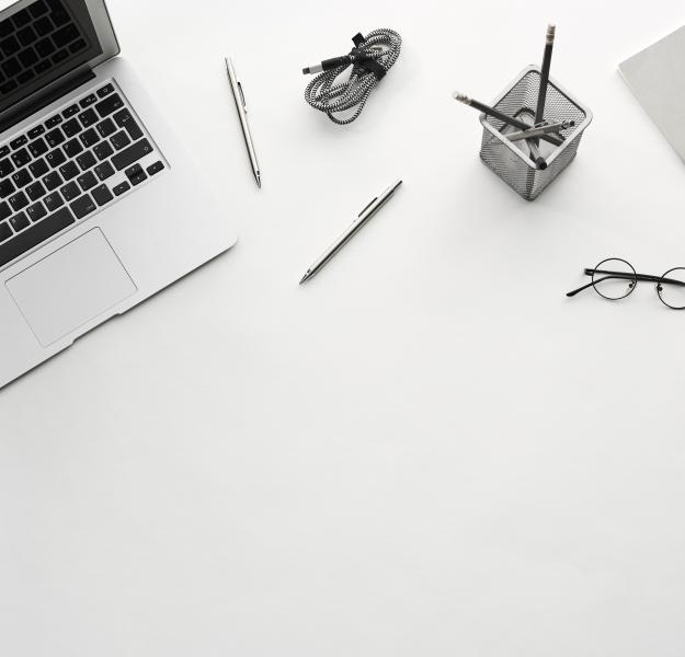 Laptop met bril, pen, laadkabel en pennenbakje